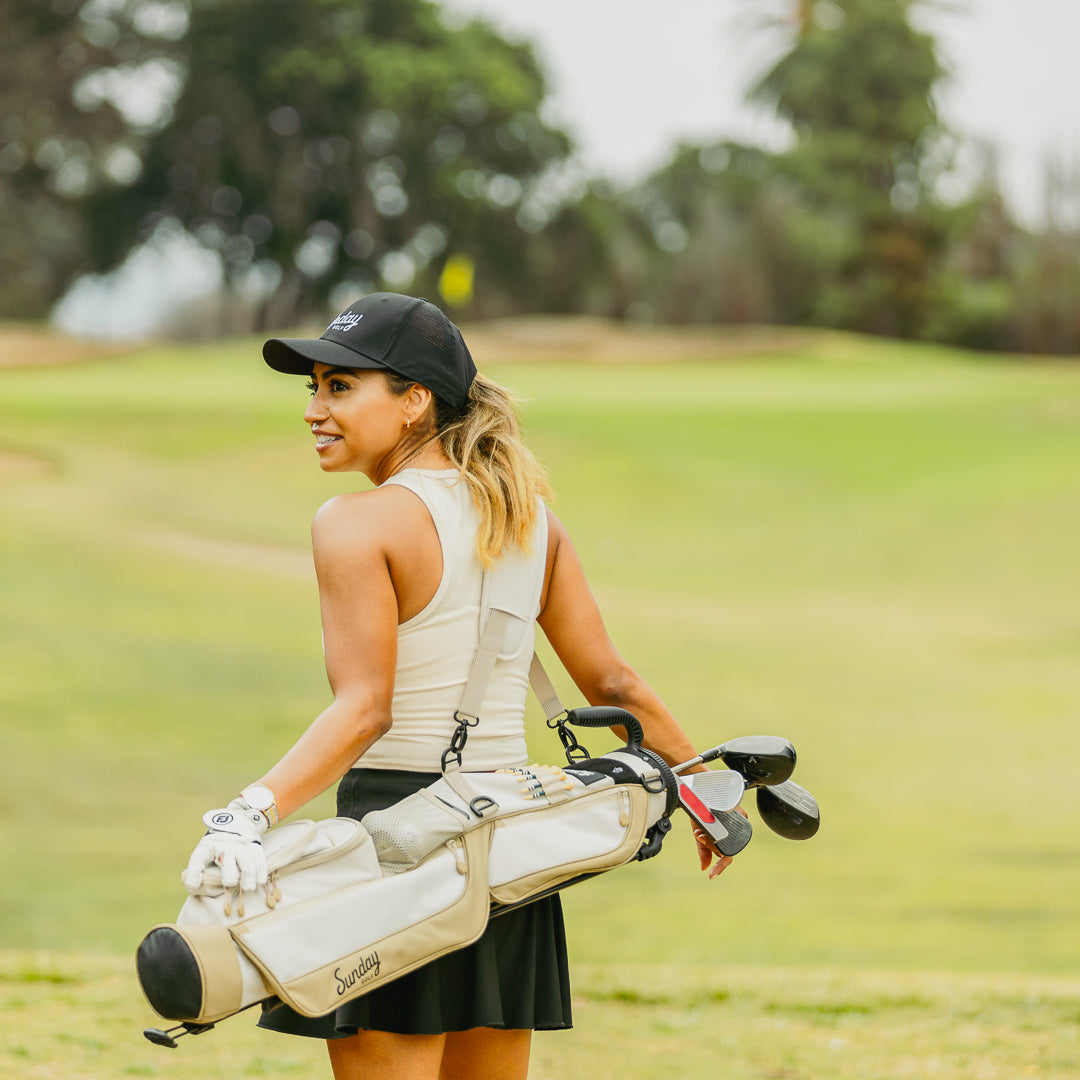 Woman carrying toasted almond Loma Bag white and tan golf bag by Sunday Golf on course