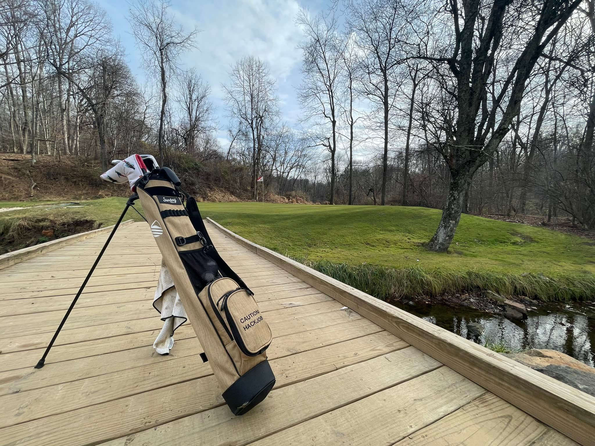 Sandstone Loma Bag by Sunday Golf on the golf course with a river and bridge