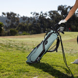 woman putting clubs in the seafoam green El Camino golf bag by Sunday Golf 