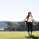 woman smiling, carrying seafoam green El Camino golf bag by Sunday Golf