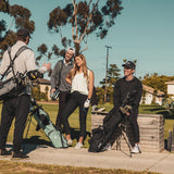 man standing with heather gray El Camino golf bag by Sunday Golf, woman standing with seafoam El Camino golf bag by Sunday Golf, and man sitting with  matte black El Camino golf bag by Sunday Golf