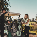 man with heather gray El Camino golf bag by Sunday Golf and woman with seafoam El Camino golf bag by Sunday Golf on a golf cart