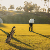 Midnight Green El Camino Golf bag by Sunday Golf on golf course with two golfers on the green putting 