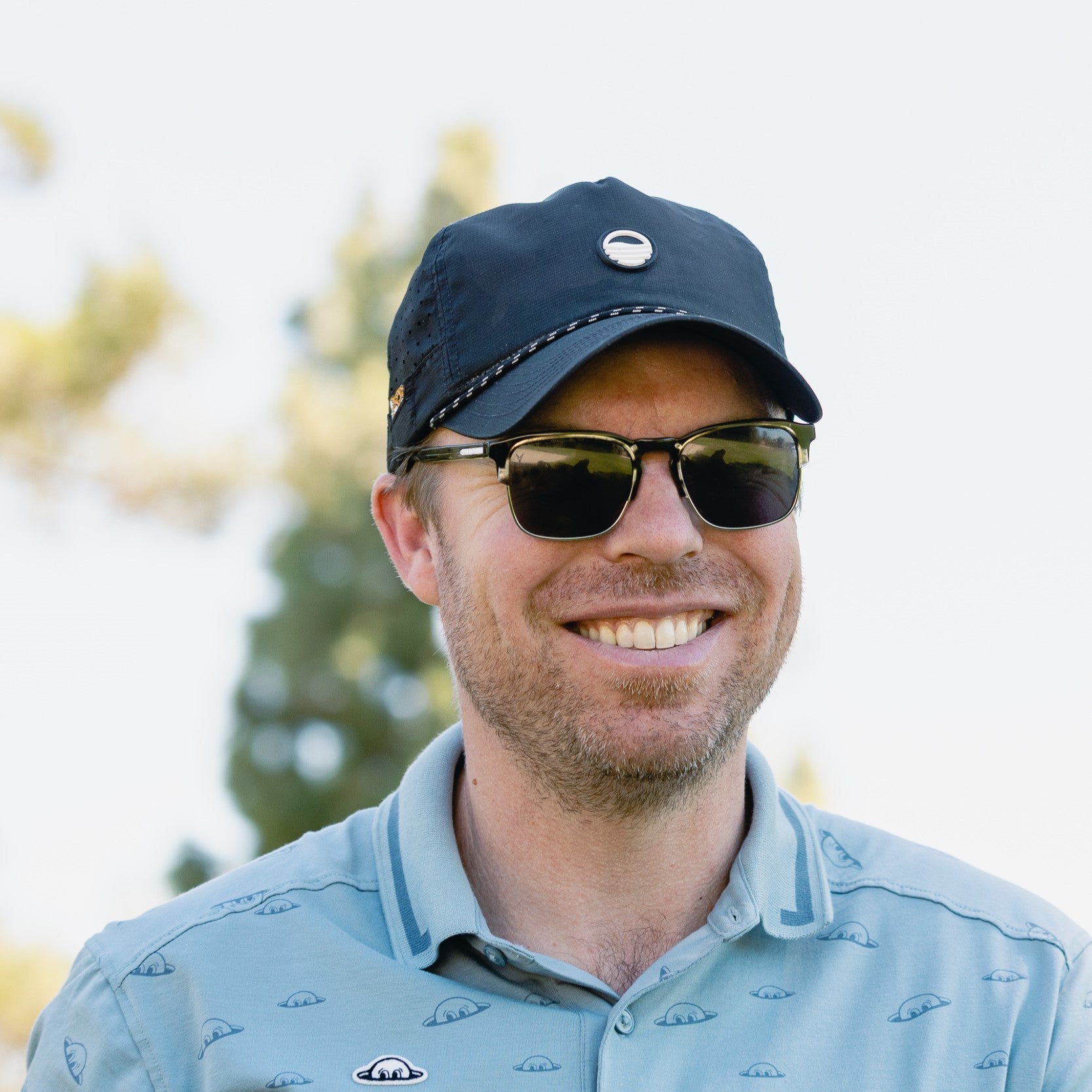 man smiling wearing black porter lite sundaze hat by sunday golf 