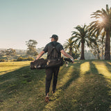 man carrying the matte black El Camino golf bag by Sunday golf on golf course with palm trees
